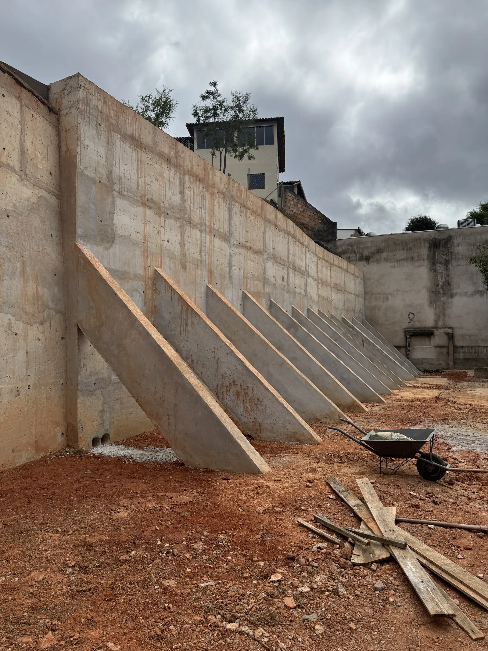 Muro de arrimo em concreto armado com contrafortes inclinados, executado em terreno com desnível